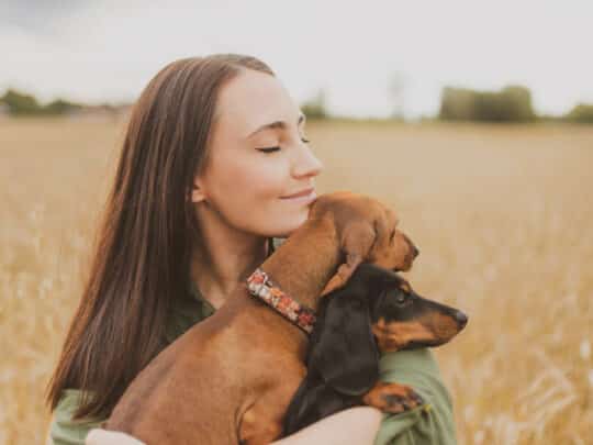 Una mujer abrazando a su perro de raza teckel